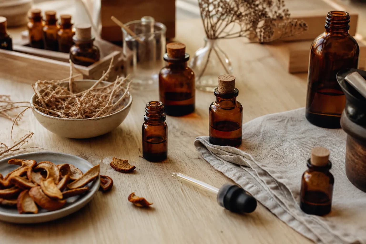 Établi du parfumeur : fioles ambrées, pipette et botaniques séchées.